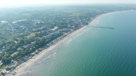 Baltic-sea-aerial-drone-view,-tourist-beach-summertime-destination-in-Scharbeutz,-Germany,-tilt-down-to-coast,-day
